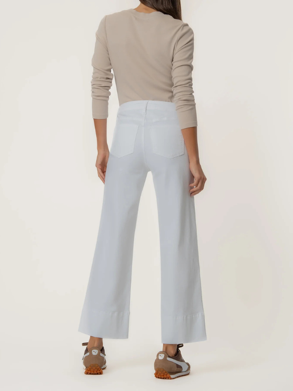 Person wearing a beige sweater and light white pants on a white background