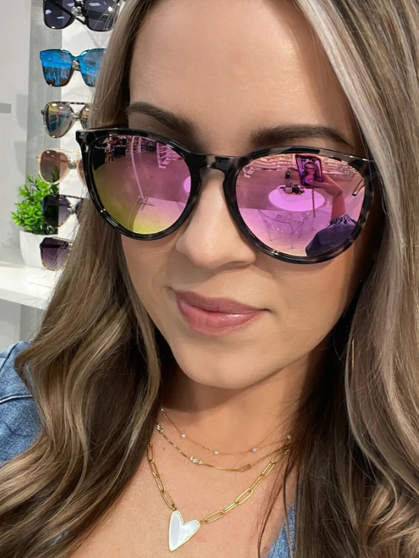 Woman wearing sunglasses with a store display of sunglasses in the background