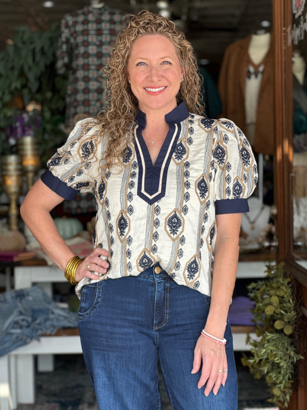 Woman wearing a patterned blouse and jeans in a store setting