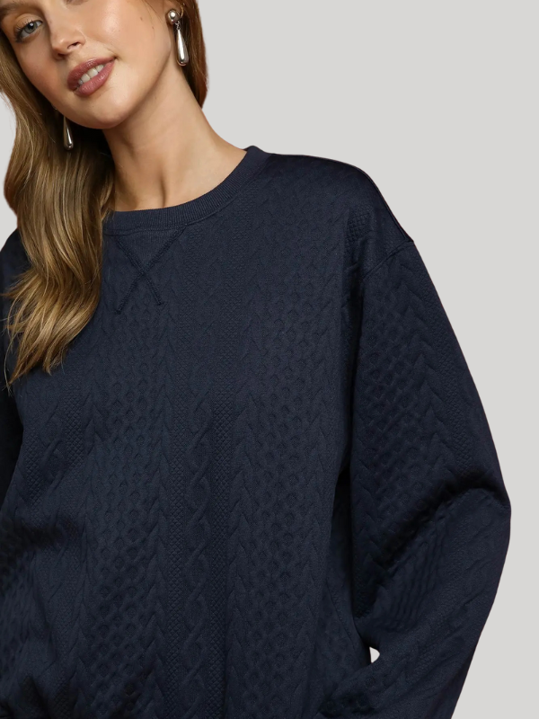 Woman wearing a navy blue textured sweater on a plain background