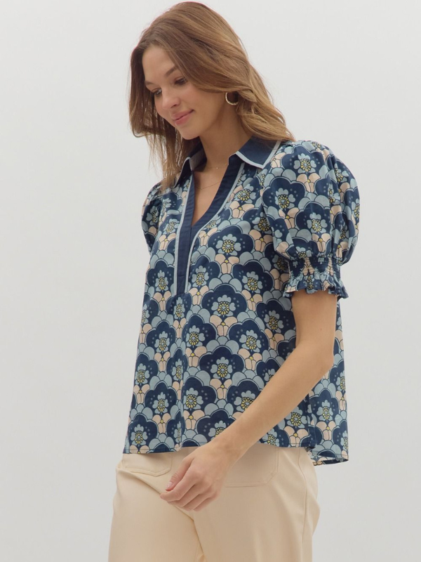 Woman wearing a blue floral blouse with beige pants on a white background