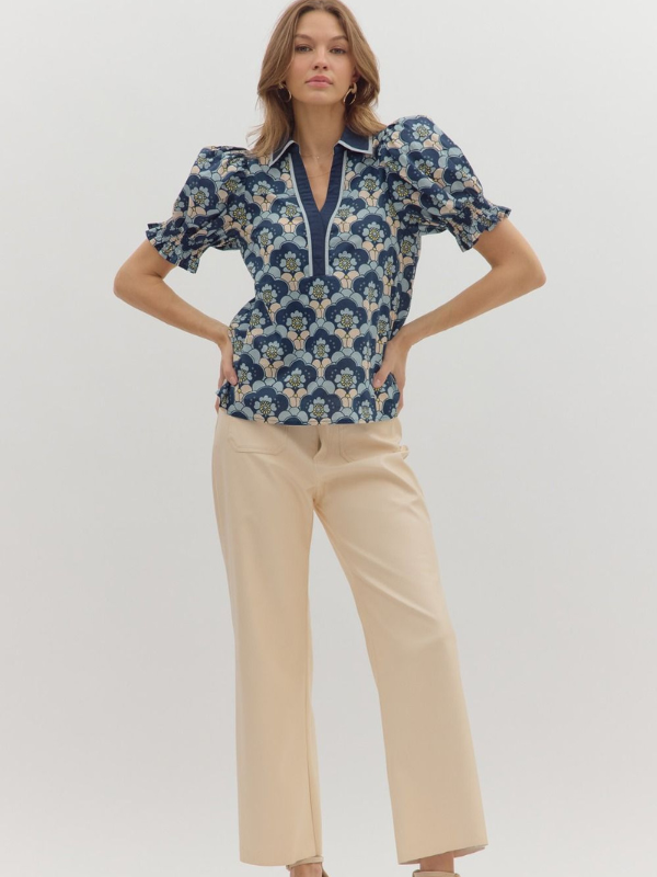 Woman wearing a blue floral blouse and beige pants on a white background