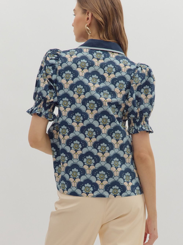 Woman wearing a blue floral patterned blouse with beige pants on a white background
