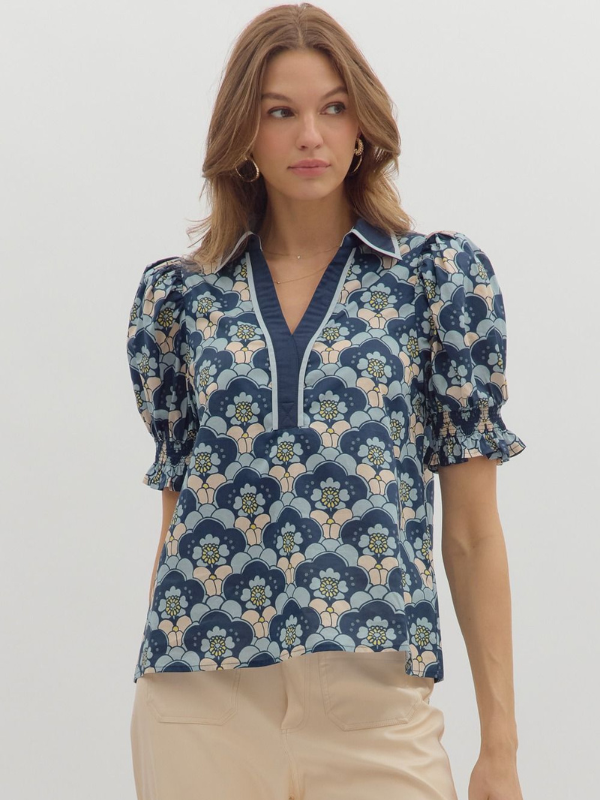 Woman wearing a floral patterned blouse with puff sleeves on a white background