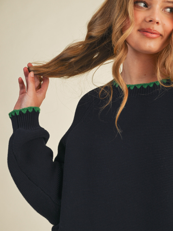 woman wearing a navy sweater with green stitching