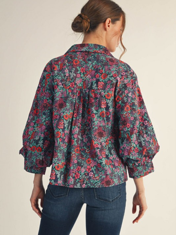 Woman wearing a floral patterned shirt with a neutral background