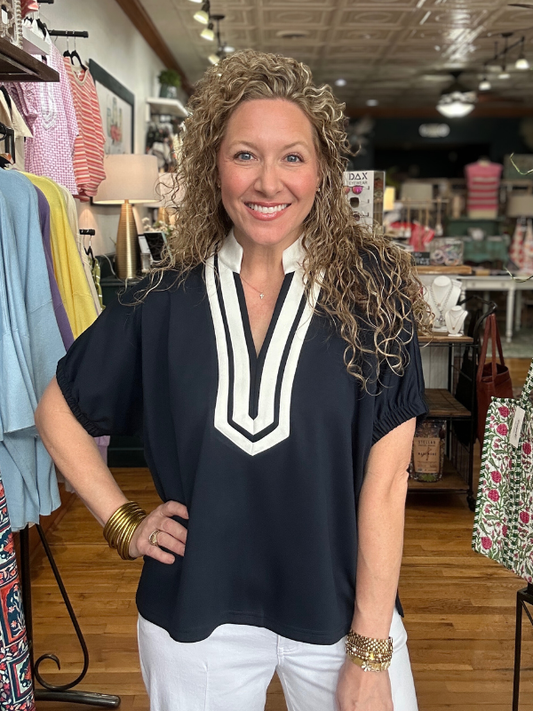 Woman wearing a black top with a white V-neck in a clothing store.