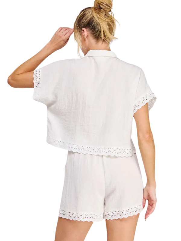 A woman shown from the back wearing a white short-sleeve cropped shirt and matching white shorts with eyelet lace trim, against a plain white background.