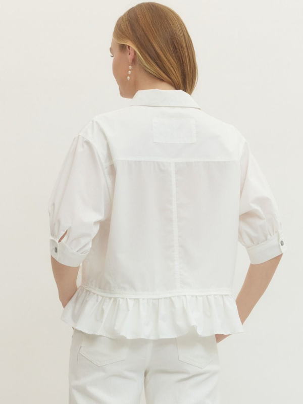 Woman wearing a white blouse with ruffled details on a plain background