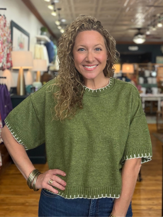 woman wearing an olive stitch sweater and denim jeans