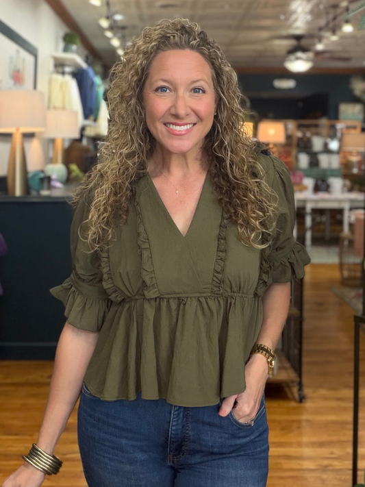 woman wearing an olive ruffle blouse and jeans