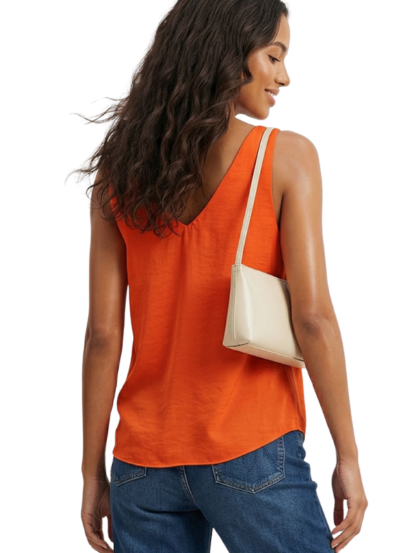 A woman shown from the back wearing a bright orange sleeveless tank top and blue jeans, carrying a small cream shoulder bag against a plain white background.