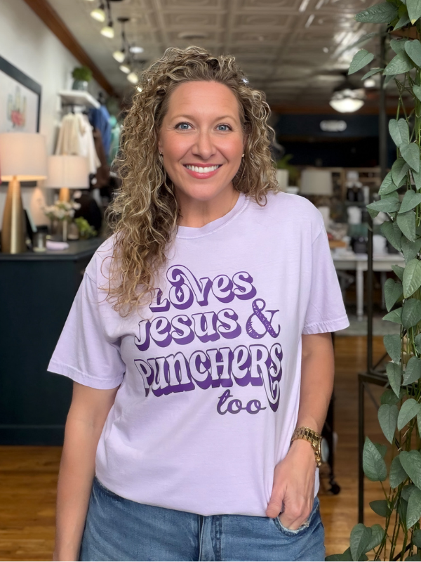 woman wearing a lavender tee that says Loves Jesus & The Punchers too in dark purple ink