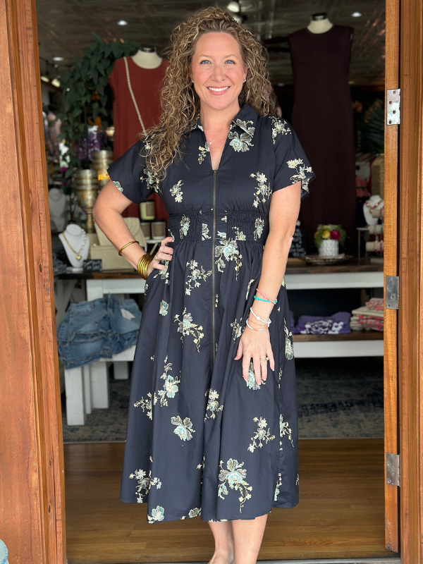 Woman wearing a navy floral dress standing in a store.