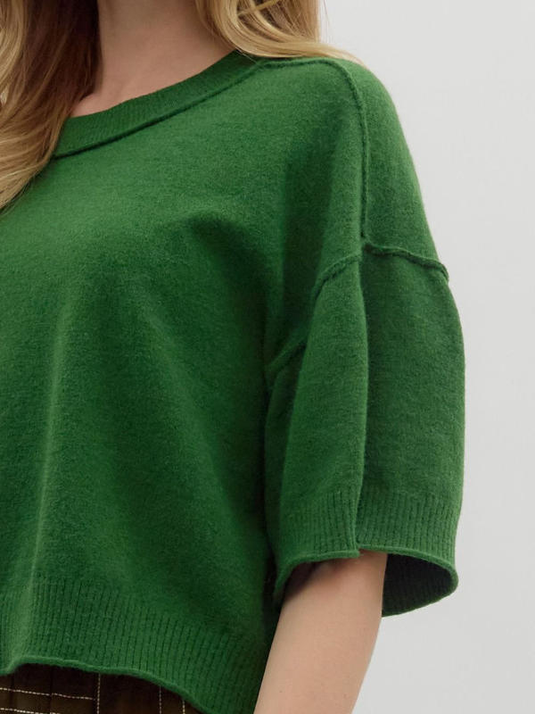 Green sweater worn by a person on a plain background
