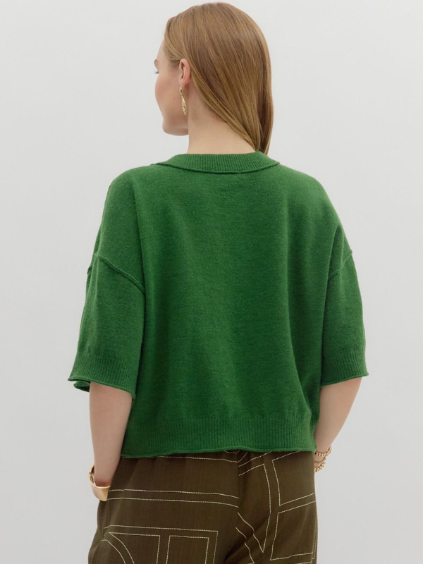 Person wearing a green sweater on a plain background