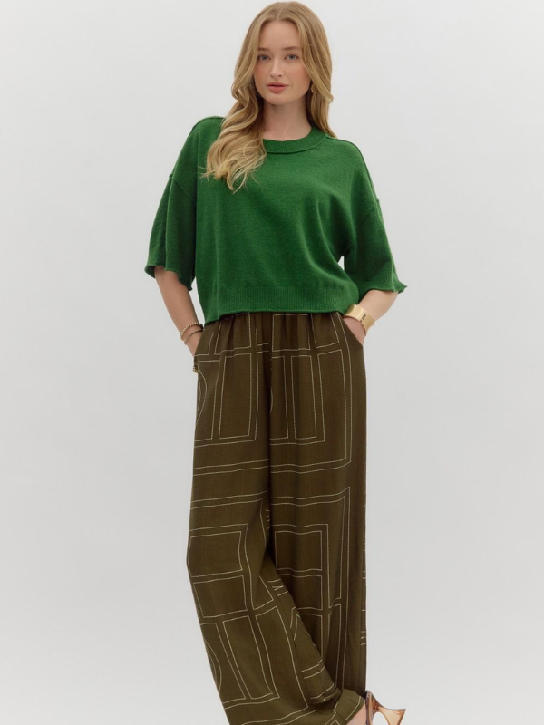 Woman wearing a green top and brown checkered pants on a white background