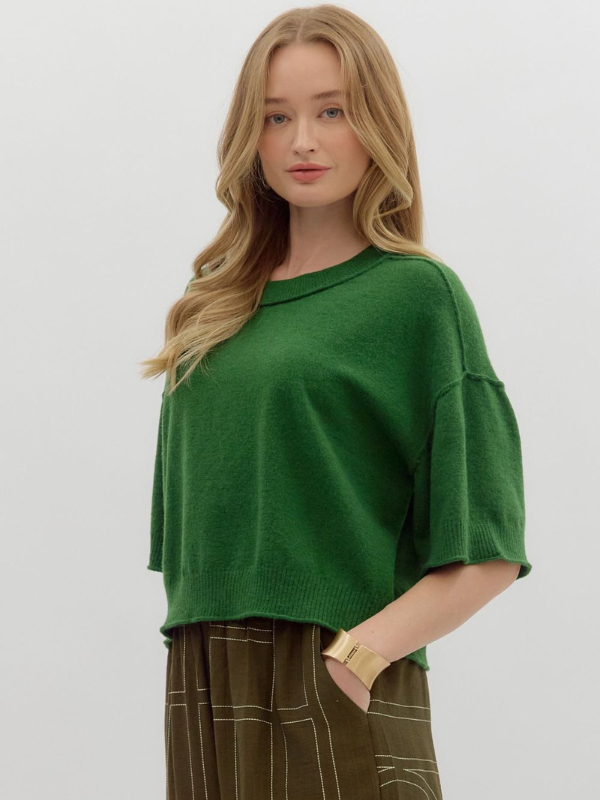 Woman wearing a green sweater against a plain background