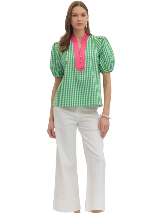Woman wearing a green checkered blouse with pink trim and white pants on a white background