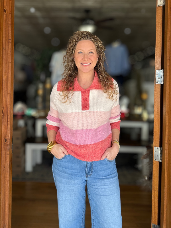 Woman wearing a striped sweater and jeans standing in a doorway.
