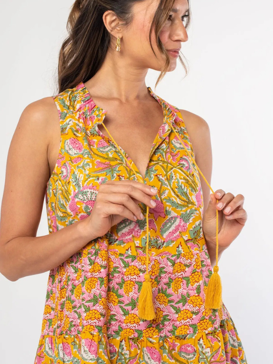 Woman wearing a floral dress with yellow tassels on a white background