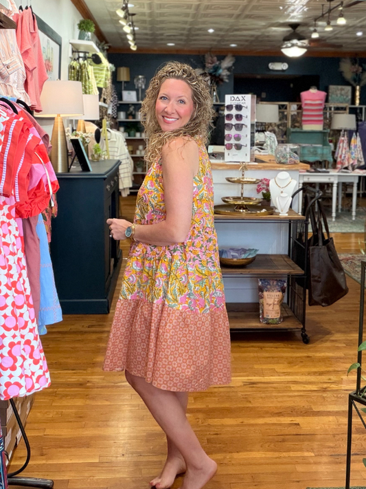 Woman in a colorful dress standing in a store with various items on display.