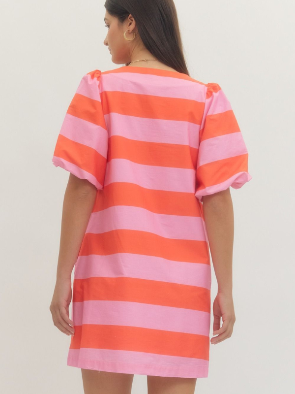 Woman wearing a pink and orange striped dress against a plain background
