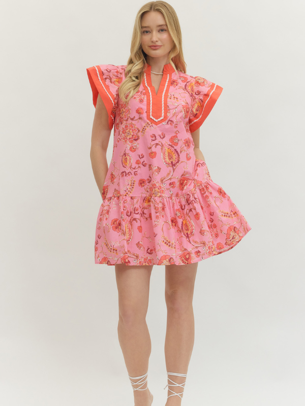 Woman wearing a pink floral dress with orange accents on a white background