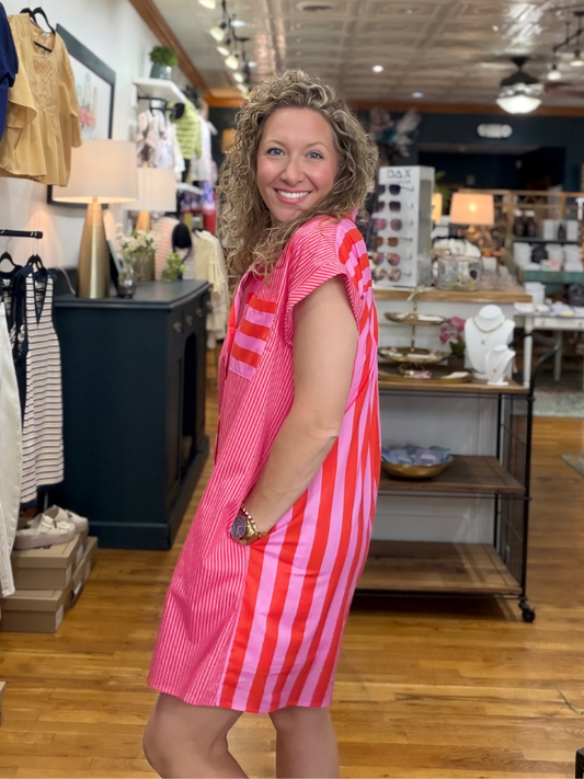 Woman wearing a pink dress with red stripes in a store setting