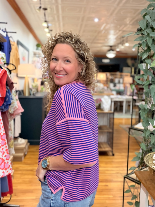 Woman wearing a purple and pink striped top in a store setting