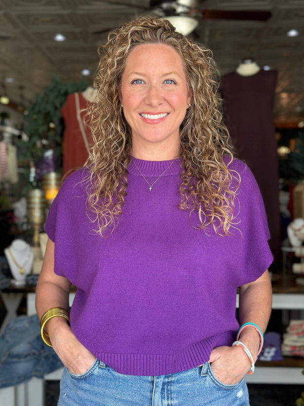 Woman wearing a purple sweater and blue jeans in an indoor setting