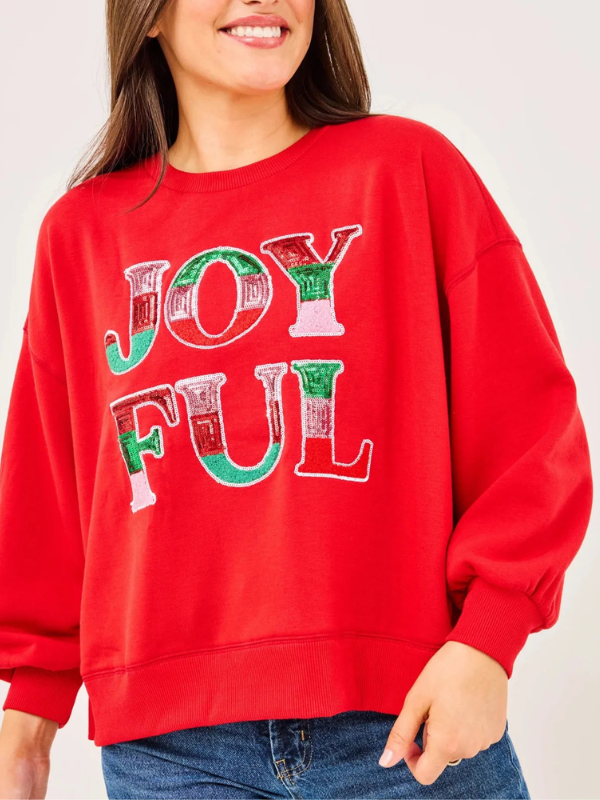 Red sweatshirt with 'JOYFUL' text in Christmas colors on a plain background