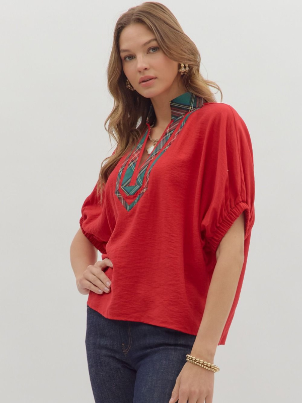 Woman wearing a red top with embroidery on a plain background