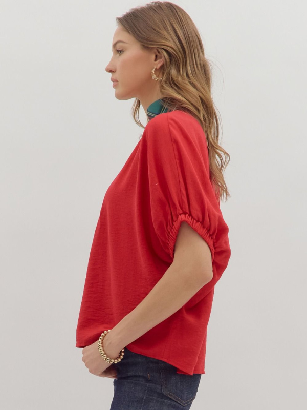 Woman wearing a red blouse with a plain background