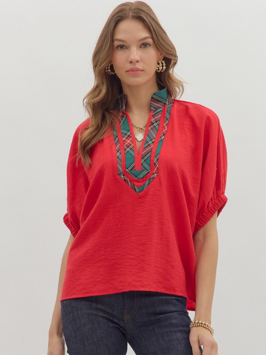 Woman wearing a red blouse with plaid neckline against a plain background