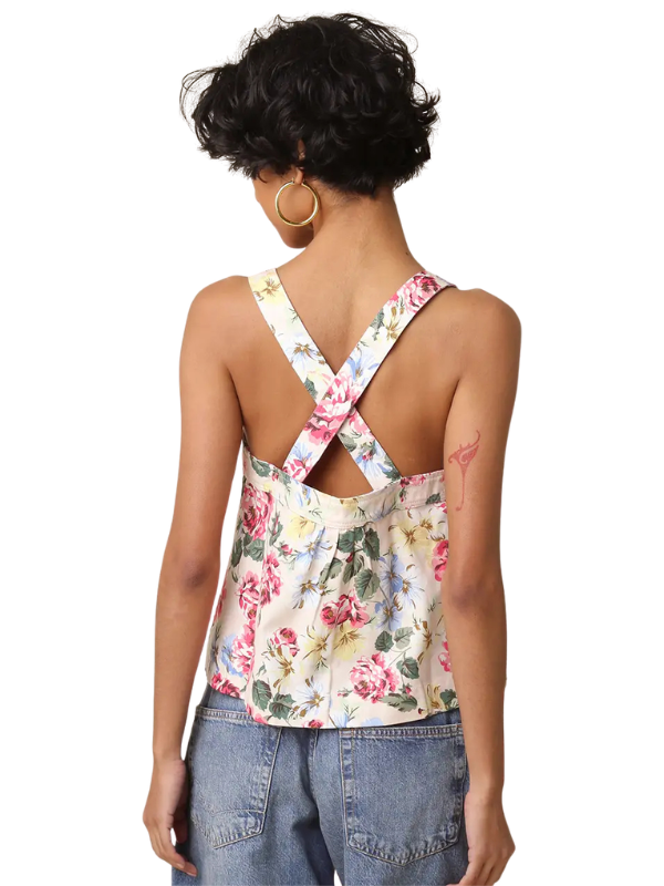 Woman wearing a floral tank top with criss-cross back design on a white background