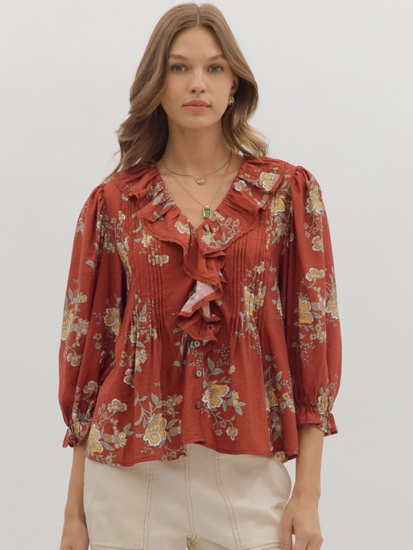 Woman wearing a red floral blouse with ruffled details on a white background