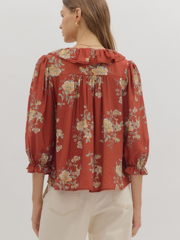 Woman wearing a floral blouse with ruffled details on a plain background