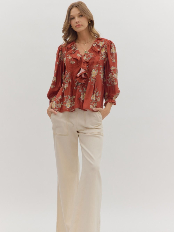 Woman wearing a red floral blouse and beige pants on a white background