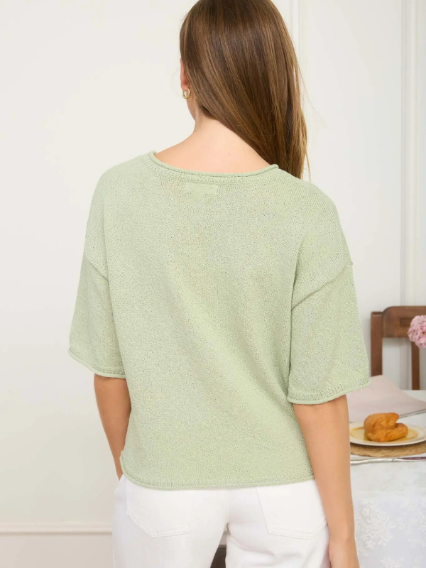 woman wearing sage green top and white pants