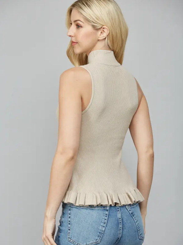 Woman wearing a beige ribbed tank top with a ruffled hem on a gray background