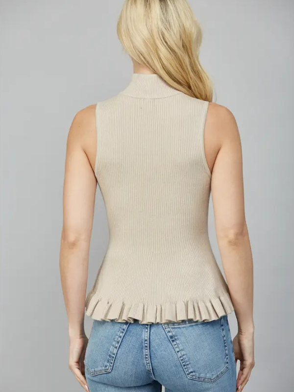Woman wearing a beige ribbed sleeveless top with a peplum waist against a gray background