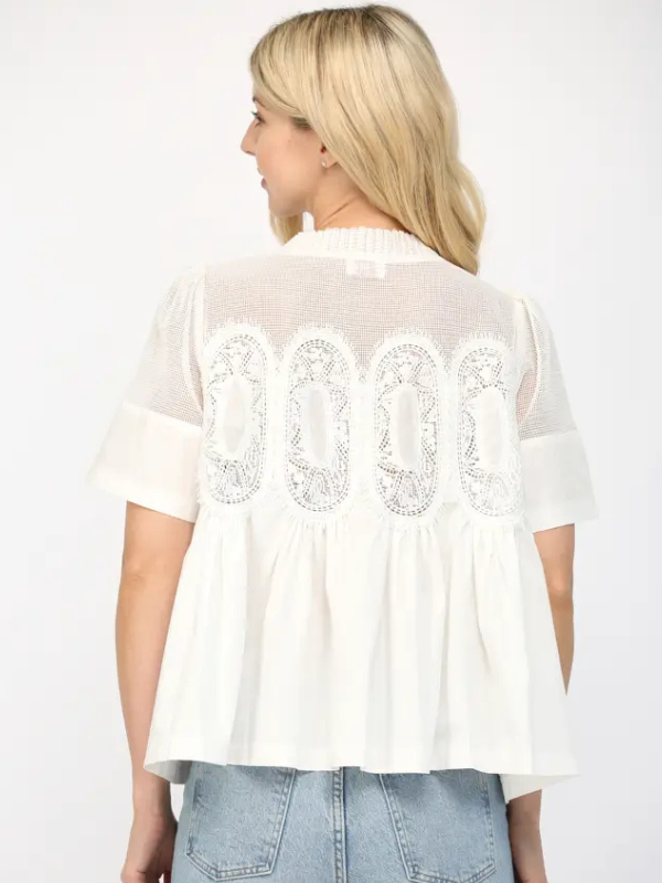 Woman wearing a white lace-trimmed blouse with a plain background