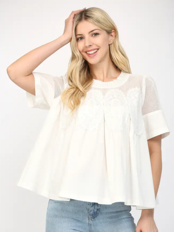 Woman wearing a white blouse with sheer sleeves against a white background
