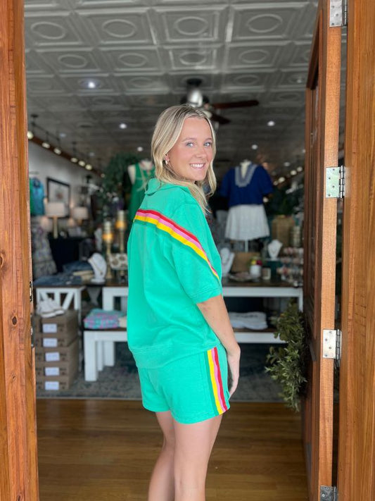 Woman wearing a green outfit with colorful stripes standing in a store.