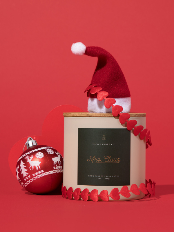 Decorative candle with Santa hat and ornament on a red background