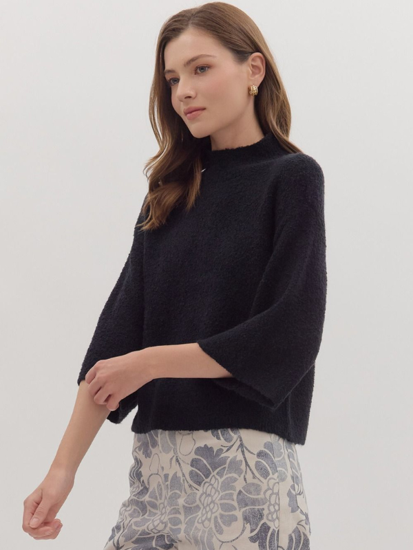 Woman wearing a black sweater with a plain background