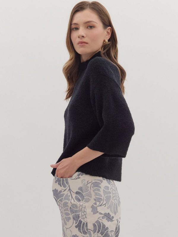 Woman wearing a dark blue sweater and patterned pants on a white background