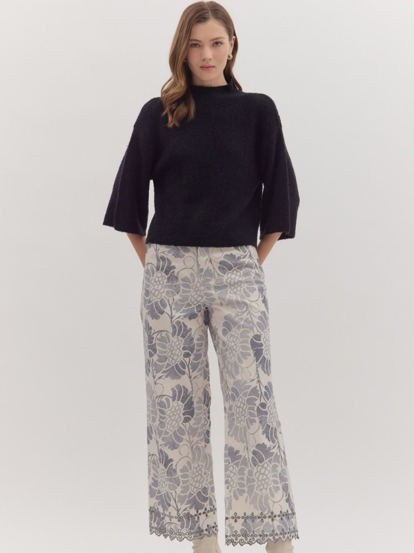 Woman wearing a black top and patterned pants on a white background
