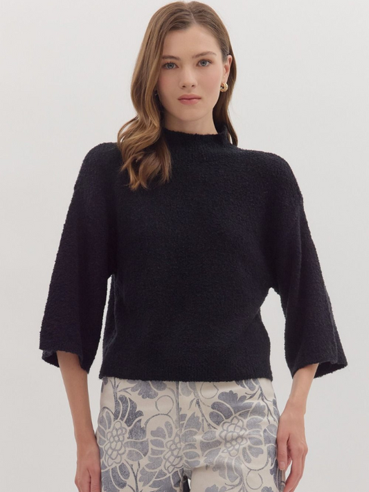Woman wearing a black sweater with floral pants on a white background